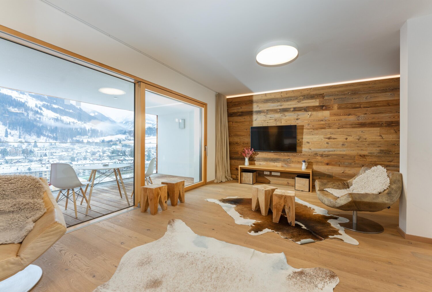 Wohnzimmer mit Holzwand, TV und Balkonblick