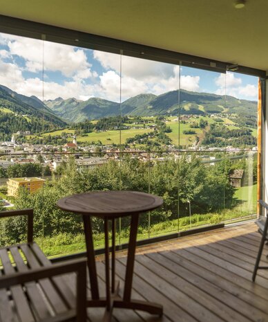 Balkon mit Holzmöbeln und Bergblick ins Tal