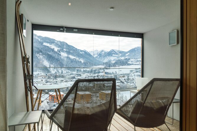 Innenraum-Balkon mit Korbsesseln und verschneiter Berglandschaft.