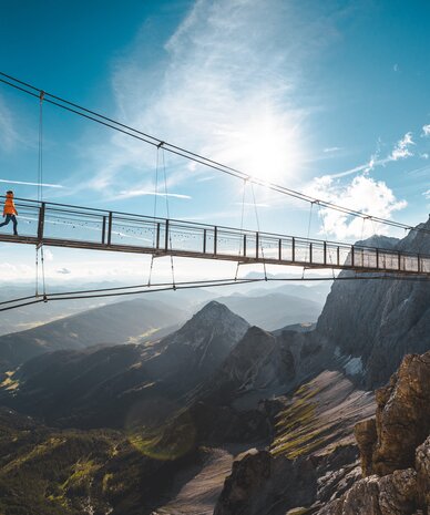Schwebende Hängebrücke über felsiges Bergtal mit Wanderer