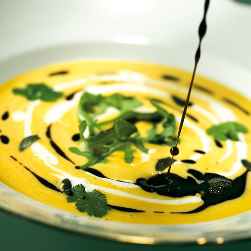 Cremige orangefarbene Suppe mit Koriander-Garnitur und Balsamico-Glasur | © Robert Sommerauer