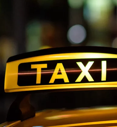 Taxi-Schild auf Auto bei Nacht, Stadtlichter im Hintergrund