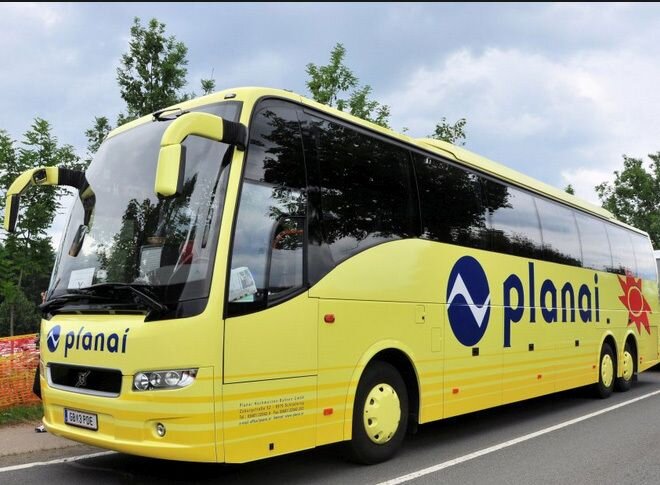 Gelber Reisebus mit Planai-Logo am Straßenrand geparkt