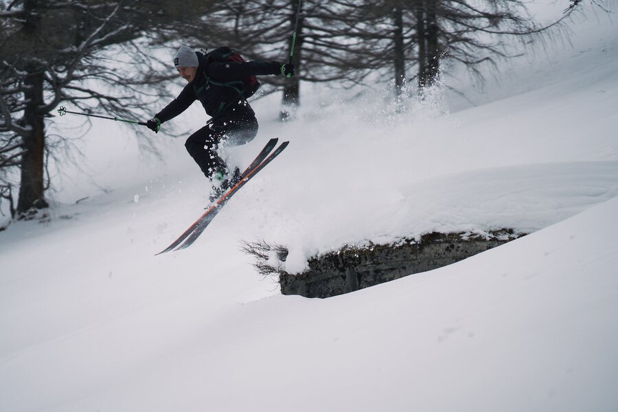 Skifahrer mit Winterausrüstung springt von einer verschneiten Rampe | © Robert Maybach
