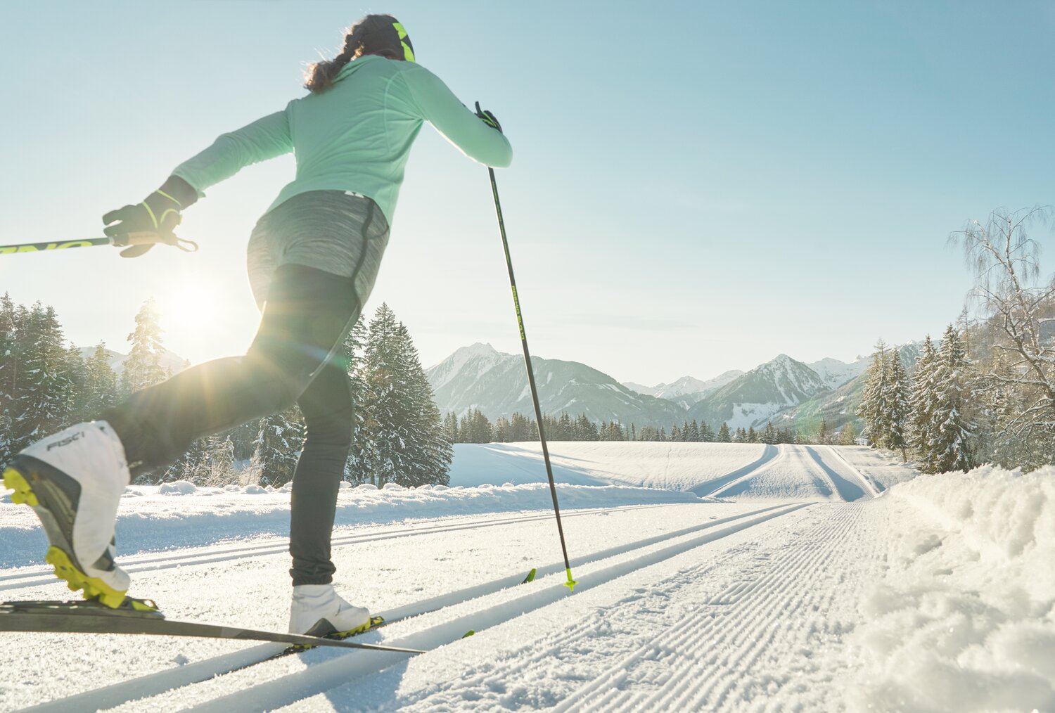Skifahrer von hinten in grüner Jacke gleitet durch verschneite Landschaft | © Peter Burgstaller
