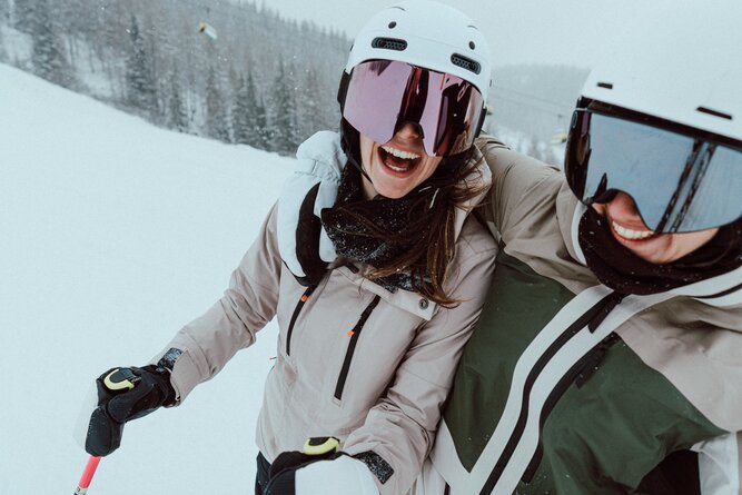 Two skiers in helmets and goggles on snowy slope