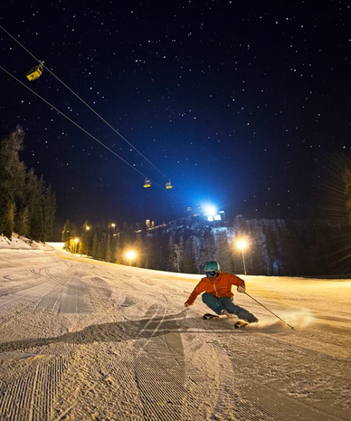 Skifahrer auf der beleuchteten Piste am Abend | © Gregor Hartl