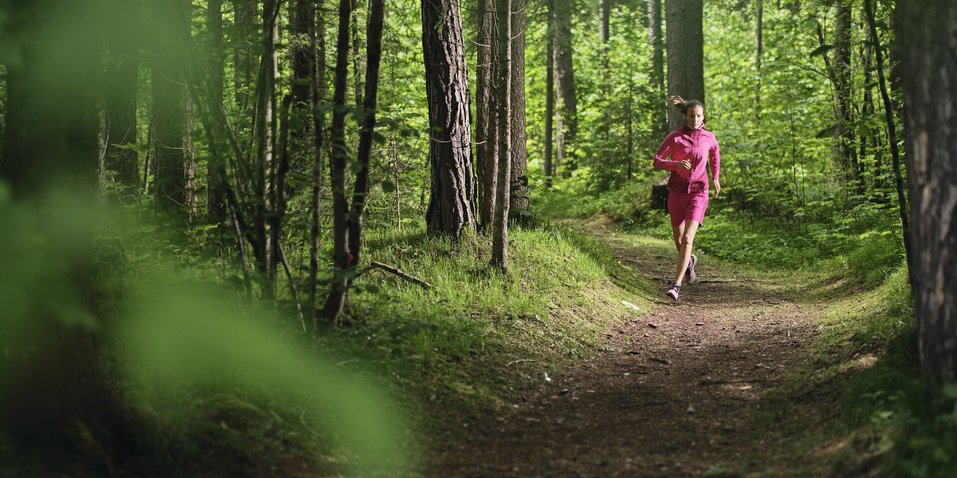 Person joggt auf Waldweg in pinker Kleidung | © RAPHAELGABAUER.COM