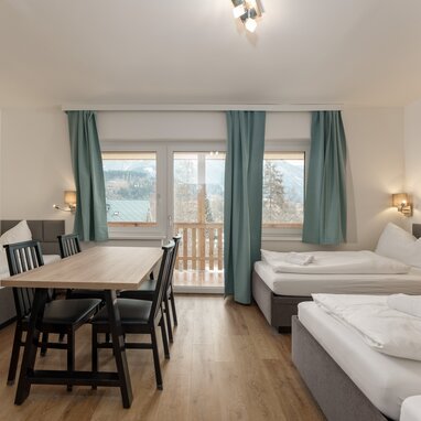 Hotel room with two beds, dining table, balcony view