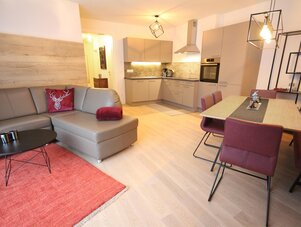 Offener Wohnbereich mit grauer Couch und roten Akzenten.