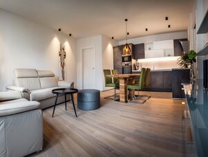 Offener Wohnbereich mit beigen Sofas, Esstisch und grünen Stühlen