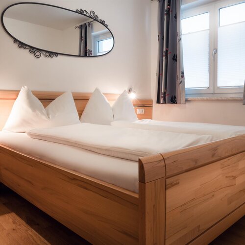 Holzbett mit weißer Bettwäsche und Kissen im Schlafzimmer