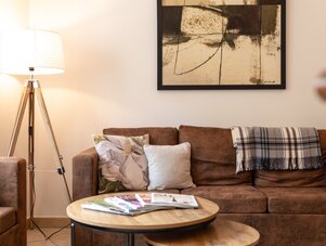 Gemütliches Wohnzimmer mit braunem Sofa, Couchtischen und Kunst.