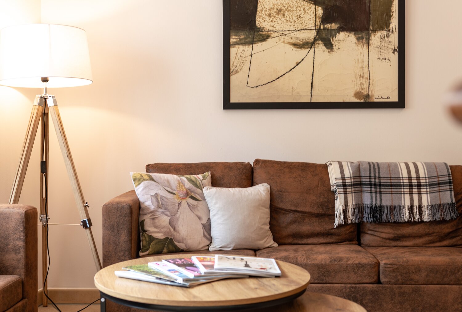 Gemütliches Wohnzimmer mit braunem Sofa, Couchtischen und Kunst.