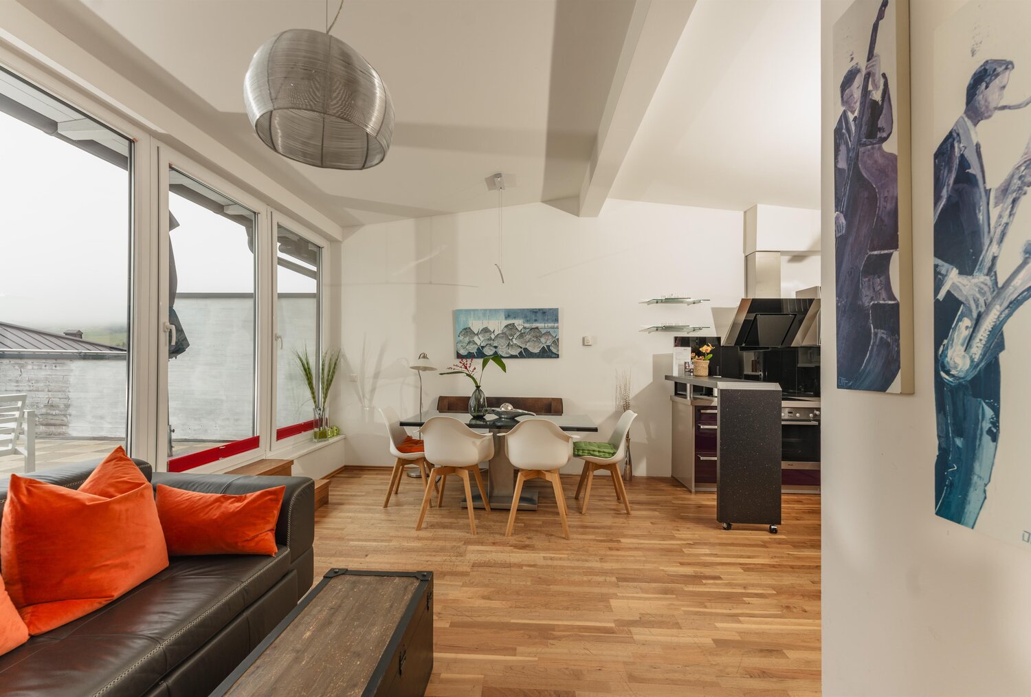 Offener Wohnbereich mit Sofa, Esstisch und großen Fenstern