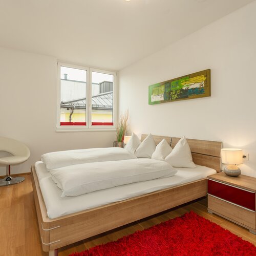 Modernes Schlafzimmer mit Holzbett und weißer Bettwäsche