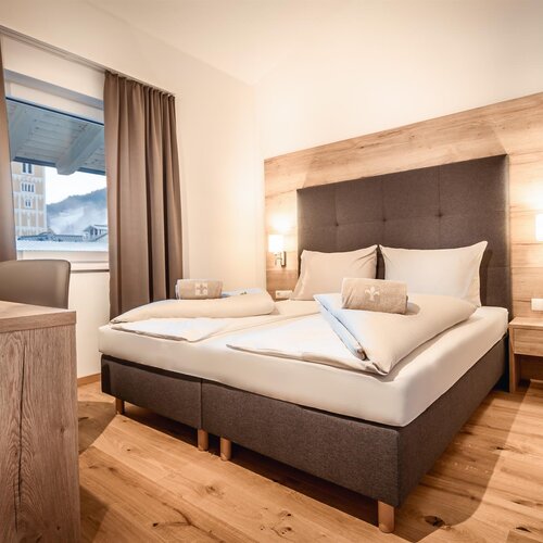 Hotelzimmer mit großem Bett, gepolstertem Kopfteil und Nachttischlampen.