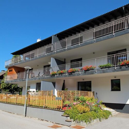 Modernes dreistöckiges Wohnhaus mit Balkonen und Blumen