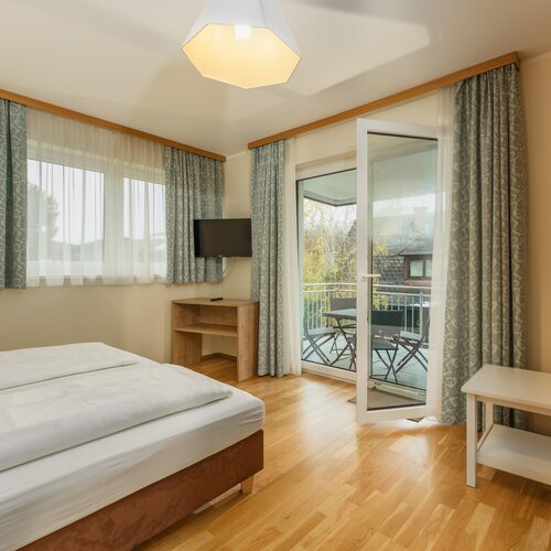 Hotelzimmer mit Doppelbett, Balkon-Türen und Sitzbereich.