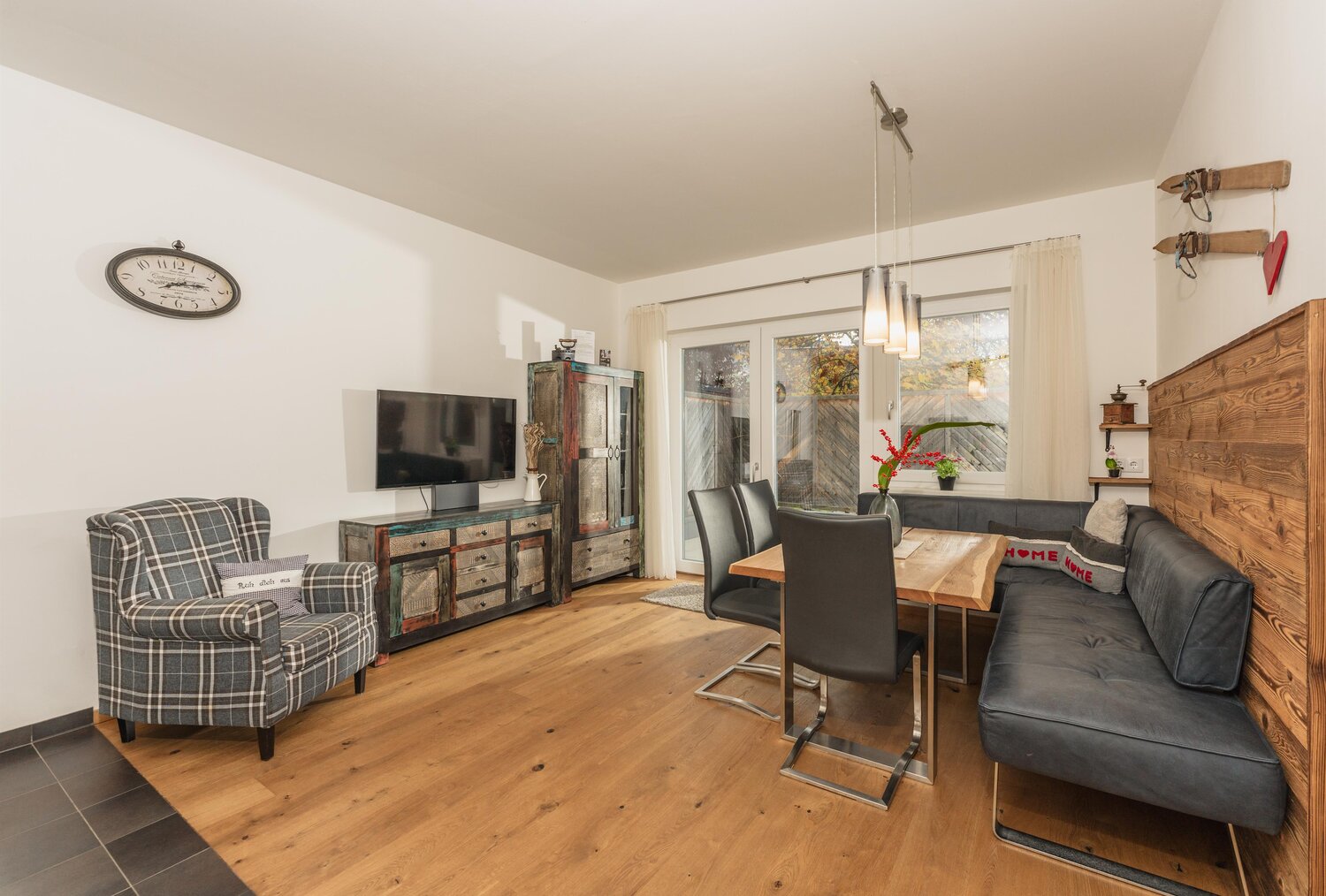 Wohnzimmer mit Esstisch, Sofa, Plaidsessel und rustikalem Sideboard