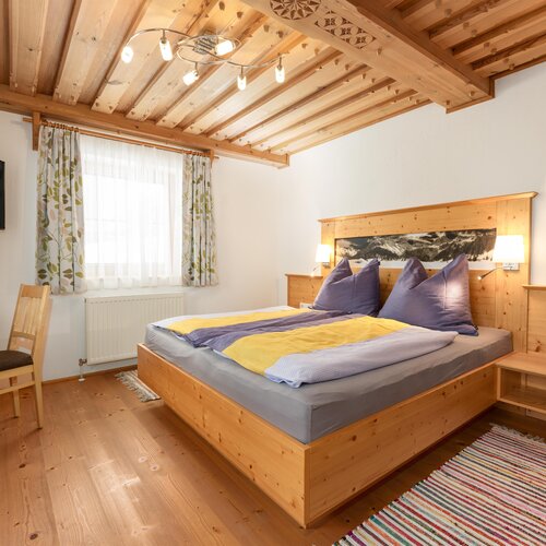 Gemütliches Holz-Schlafzimmer mit großem Bett, Nachttischen und Lampen