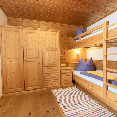 Gemütliches Schlafzimmer aus Holz mit Hochbett und Kleiderschrank