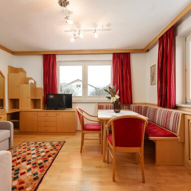 Gemütliches Wohnzimmer mit Holzmöbeln und roten Vorhängen