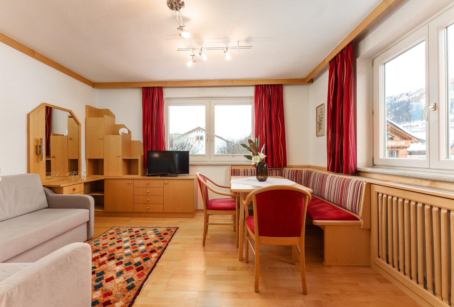 Gemütliches Wohnzimmer mit Holzmöbeln und roten Vorhängen