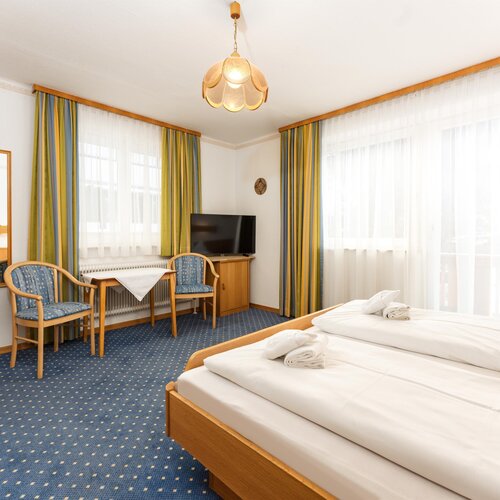 Hotelzimmer mit zwei Betten, Tisch und Sitzecke.