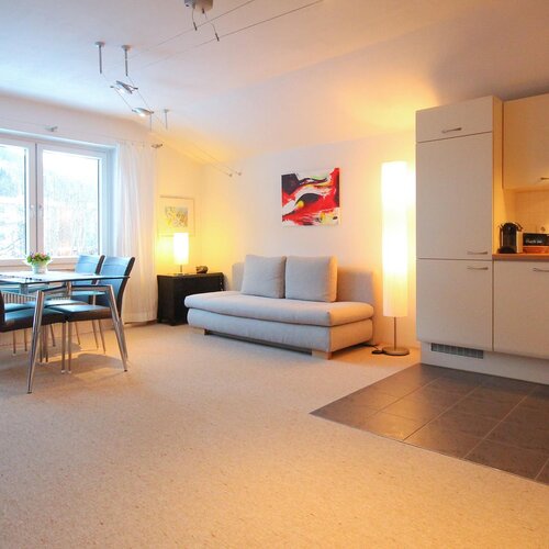 Heller offener Wohnraum mit Sofa, Esstisch und Küche.