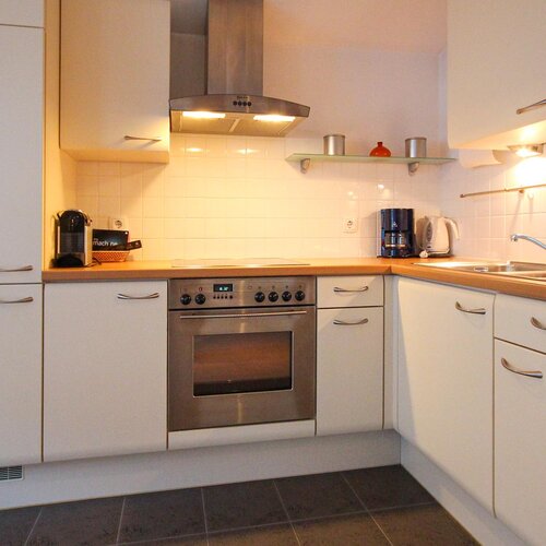 Moderne weiße Küche mit Edelstahlgeräten und Spüle