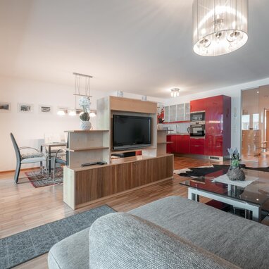 Offener Wohnbereich mit roter Küche und Essbereich | © TIEBER