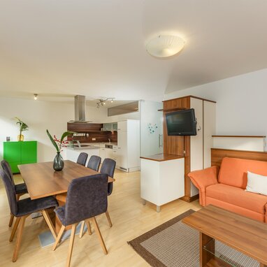 Offener Wohnbereich mit orangefarbener Couch und Esstisch