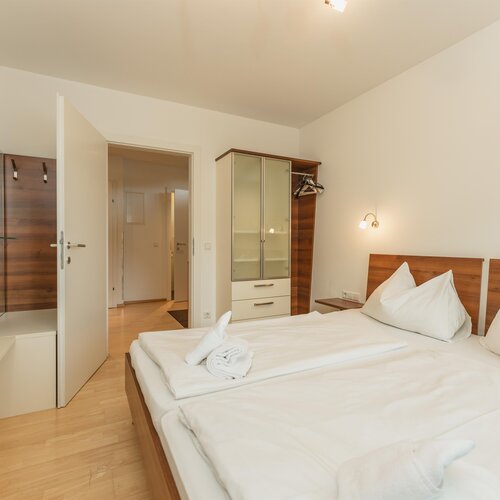 Helles Hotelzimmer mit Doppelbett und Kleiderschrank