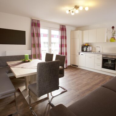 Offener Wohnbereich mit Esstisch, Stühlen und moderner Küche