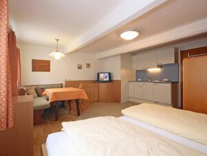 Schlafzimmer-Suite mit Küchenzeile, zwei Betten und Sofa.