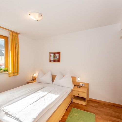 Helles Hotelzimmer mit Doppelbett, Nachttischen und Holzmöbeln