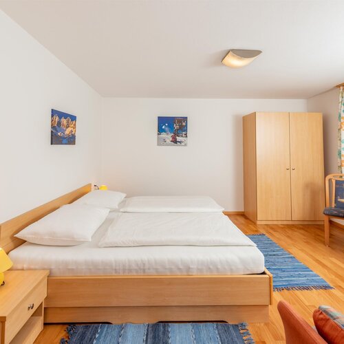 Helles Hotelzimmer mit großem Bett, Kleiderschrank und Arbeitsplatz