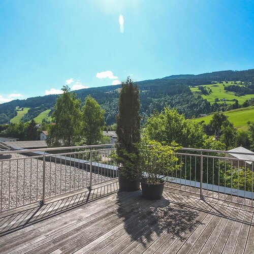 Dachterrasse aus Holz mit Blumentöpfen und Blick ins Tal