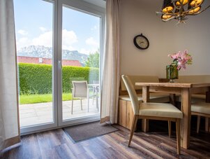 Esszimmer mit Holztisch und Stühlen neben Glas-Schiebetür zur Terrasse