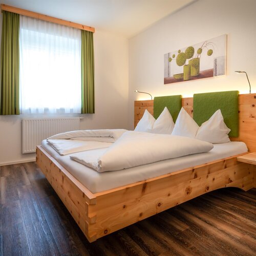 Holzbett mit grünem Kopfteil im Hotelzimmer