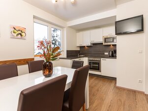 Moderne Küche mit weißer Front, Esstisch und TV