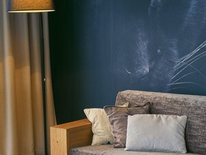 Wohnzimmer mit dunkelblauer Wand und Katzenaugen-Mural