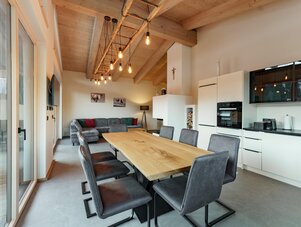 Offener Küchen- und Essbereich mit Holzbalken und Glastüren