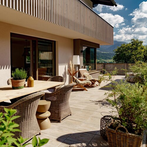 Terrasse mit Holztisch, Korbstühlen und Topfpflanzen