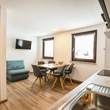 Offener Wohnbereich mit Sofa, Esstisch und Küche