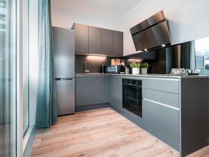 Moderne Küche mit grauen Schränken und Edelstahlgeräten.