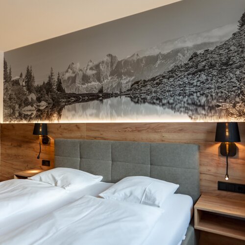 Hotelzimmer mit großer Berglandschaft über dem Bett