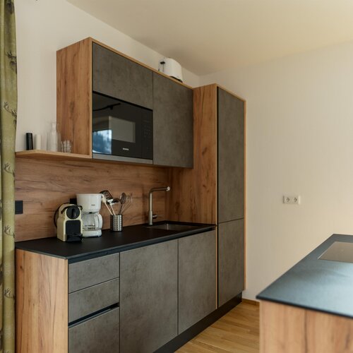 Moderne Küche mit Holz- und grauen Schränken, Spüle, Kaffeemaschine.