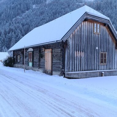 Snowy rural cabin with wooden walls in mountain landscape